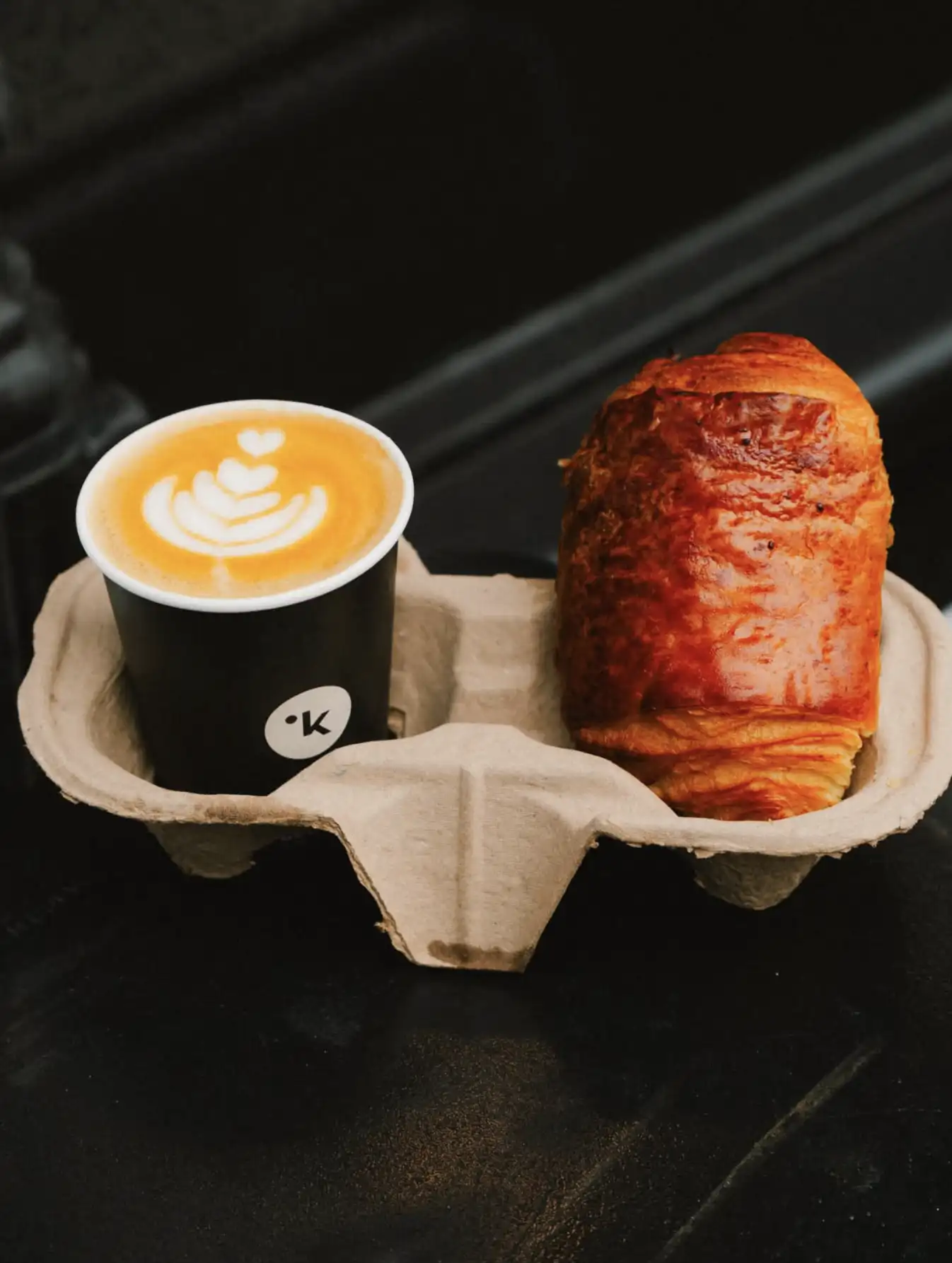 flat white with latte art beside a fresh croissant